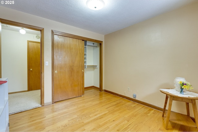 unfurnished bedroom featuring a textured ceiling, light wood-type flooring, and a closet