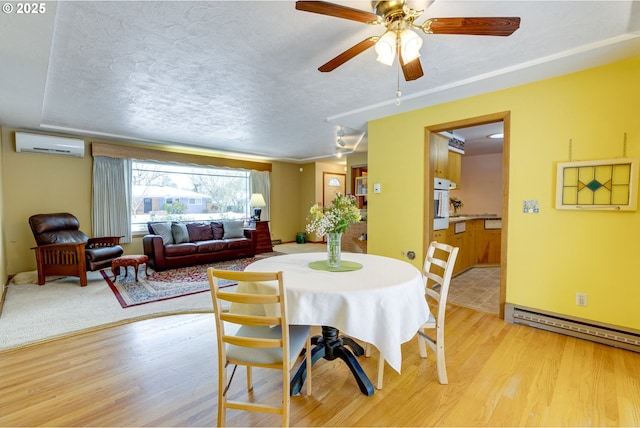 dining space featuring a wall mounted AC, light hardwood / wood-style floors, and a textured ceiling