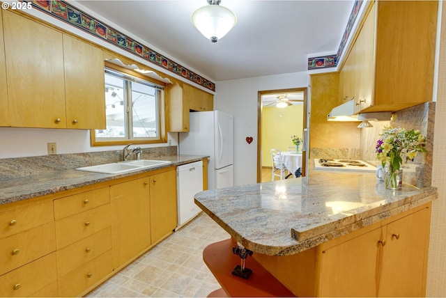 kitchen featuring sink, kitchen peninsula, white appliances, light stone countertops, and decorative backsplash