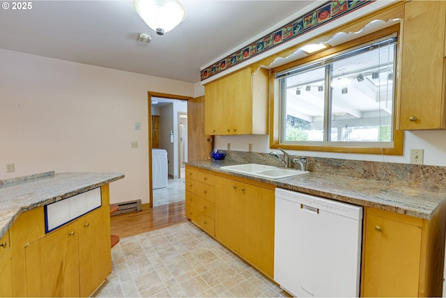 kitchen with white dishwasher, washer / dryer, sink, and light stone countertops