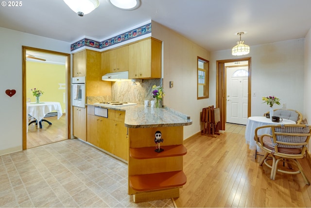 kitchen with decorative light fixtures, tasteful backsplash, light hardwood / wood-style floors, kitchen peninsula, and white appliances