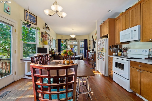 kitchen with light countertops, white appliances, visible vents, and brown cabinets