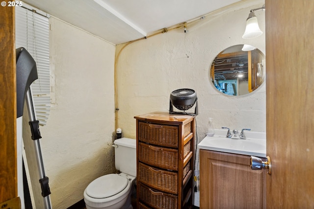 bathroom with toilet, a textured wall, and vanity