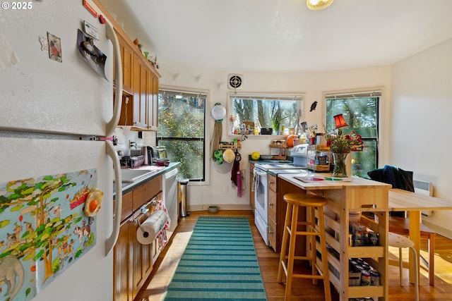 kitchen featuring light wood-style floors, white appliances, light countertops, and brown cabinets