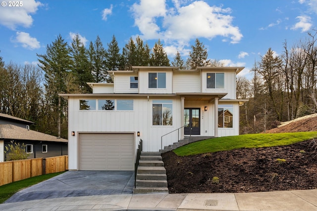 view of front of house with a garage, concrete driveway, fence, and board and batten siding