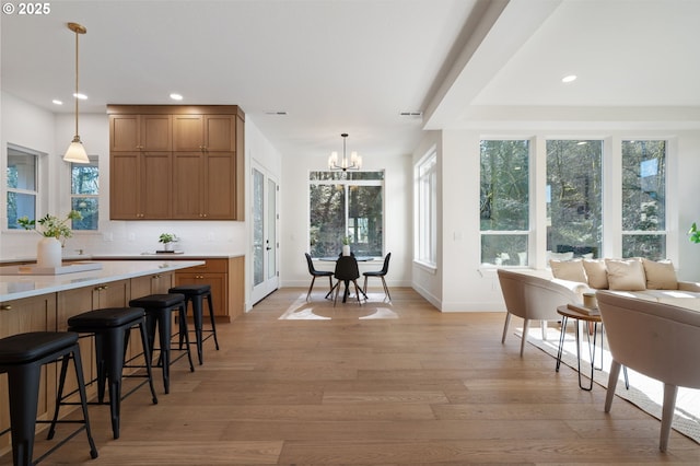 kitchen featuring a breakfast bar, light wood-type flooring, pendant lighting, and an inviting chandelier