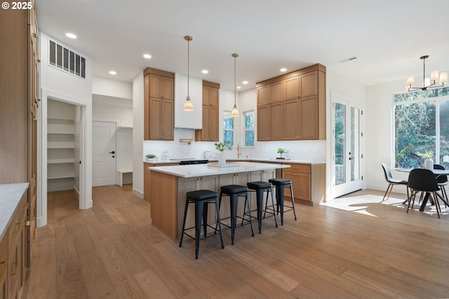 kitchen featuring light countertops, light wood-style floors, visible vents, and a kitchen breakfast bar