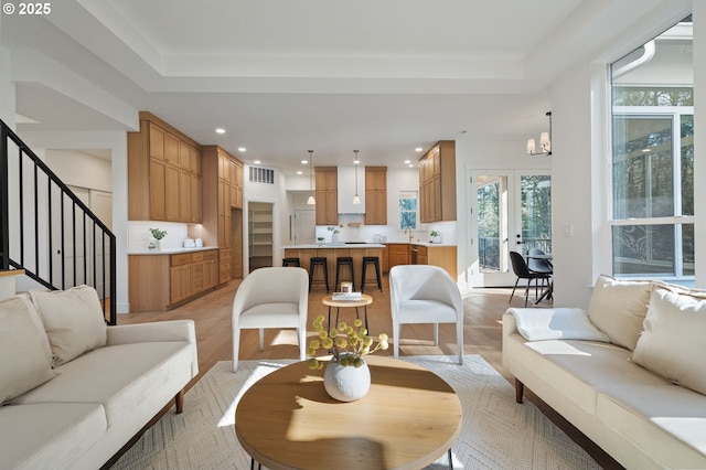 living area with recessed lighting, visible vents, light wood-style flooring, a chandelier, and stairs