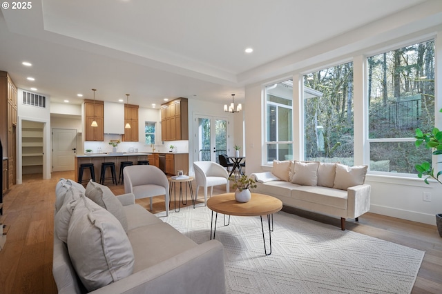 living area featuring light wood-style floors, baseboards, visible vents, and recessed lighting