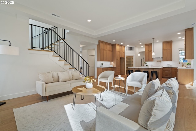 living room with recessed lighting, visible vents, stairway, light wood-style floors, and baseboards