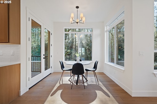 dining area featuring light wood-style floors, baseboards, and a chandelier