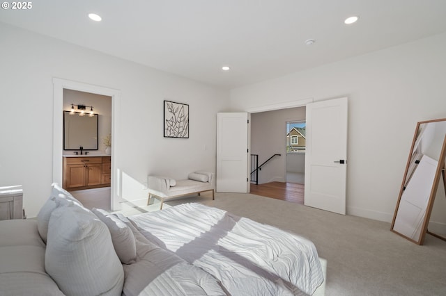 bedroom with baseboards, ensuite bath, light colored carpet, and recessed lighting