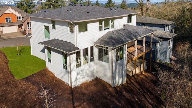 back of house with a sunroom, roof with shingles, and a yard