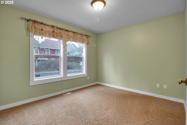 spare room featuring a textured ceiling, carpet floors, visible vents, and baseboards