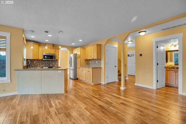 kitchen with tasteful backsplash, arched walkways, a peninsula, stainless steel appliances, and light wood-type flooring