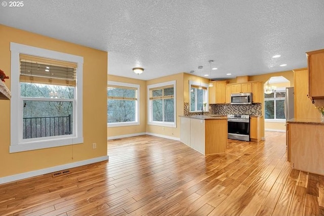 kitchen featuring tasteful backsplash, appliances with stainless steel finishes, visible vents, and light wood-style floors