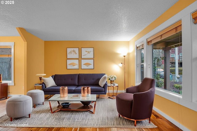 living room with visible vents, baseboards, a textured ceiling, and wood finished floors