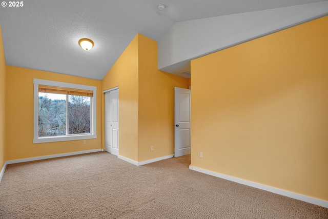 interior space featuring lofted ceiling, a textured ceiling, carpet floors, baseboards, and a closet