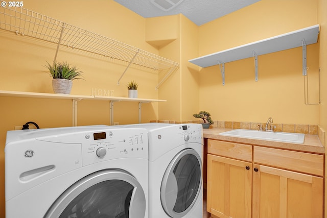 laundry room with visible vents, washing machine and clothes dryer, a sink, and cabinet space