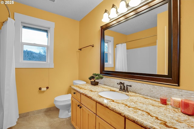 bathroom with backsplash, toilet, vanity, tile patterned flooring, and baseboards