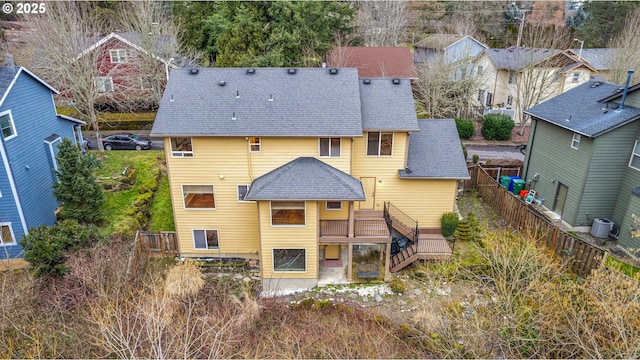 back of property with central AC unit, fence, roof with shingles, a wooden deck, and a residential view