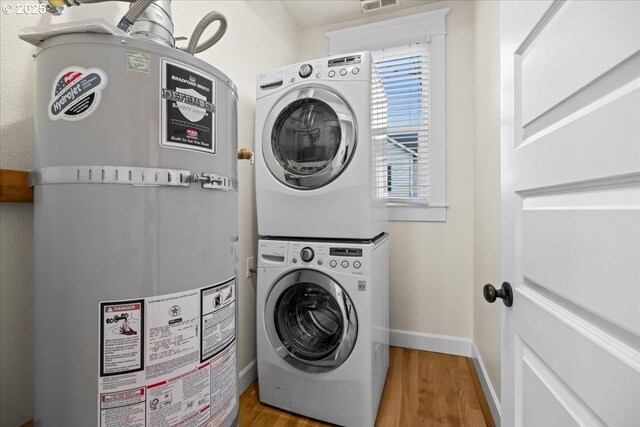 laundry area with stacked washing maching and dryer, gas water heater, and wood-type flooring