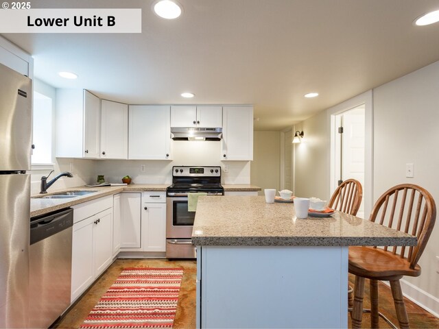 kitchen with a center island, white cabinets, sink, a breakfast bar area, and stainless steel appliances