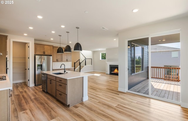 17437 NW Antonio St, Portland, OR 97229 - kitchen featuring a sink, a lit fireplace, appliances with stainless steel finishes, open floor plan, and light wood-type flooring