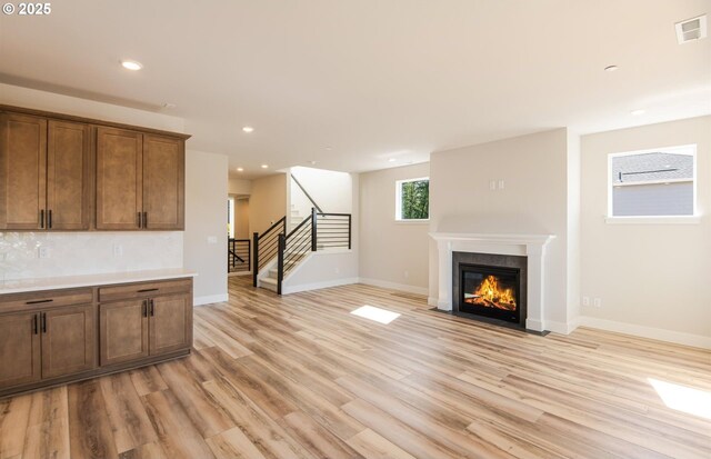 17437 NW Antonio St, Portland, OR 97229 - unfurnished living room featuring stairway, light wood-style floors, a fireplace with flush hearth, recessed lighting, and baseboards