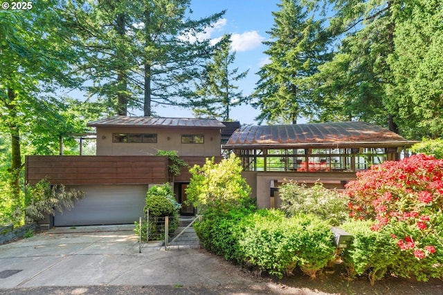 4183 SW Greenleaf Dr, Portland, OR 97221 - view of front facade featuring a standing seam roof, a garage, driveway, stucco siding, and metal roof