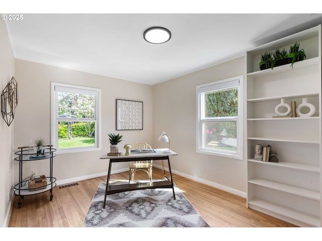 office area featuring baseboards, visible vents, plenty of natural light, and light wood-style floors
