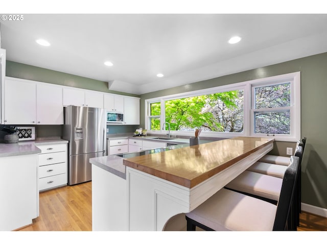 kitchen with white cabinets, a sink, a breakfast bar area, stainless steel appliances, and a peninsula