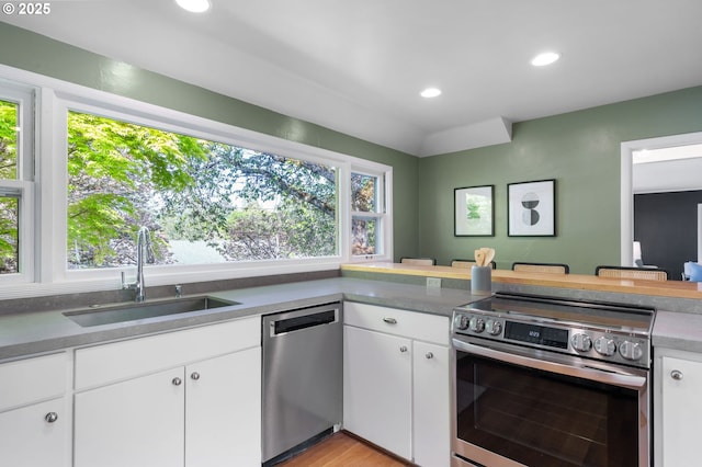 8075 SW Valley View Ct, Portland, OR 97225 - kitchen featuring stainless steel appliances, a peninsula, white cabinets, a kitchen bar, and recessed lighting