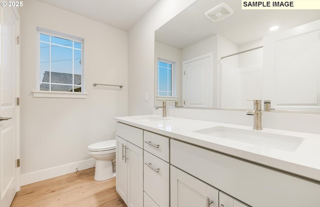 full bathroom with baseboards, wood finished floors, toilet, double vanity, and a shower