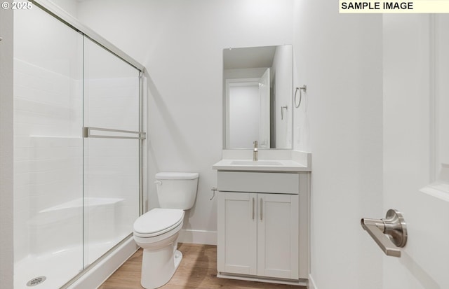full bathroom featuring a stall shower, toilet, wood finished floors, and baseboards