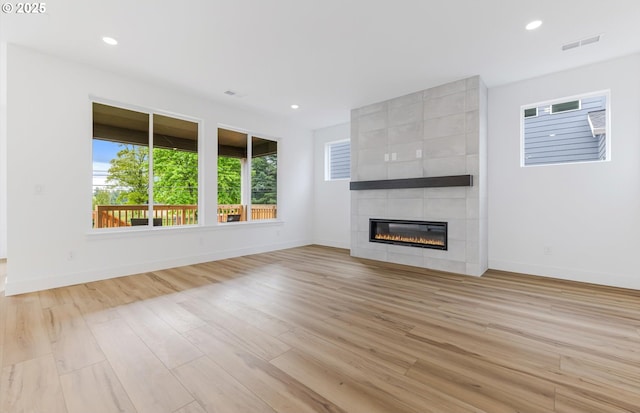 27226 SW Yarrow Ln, Wilsonville, OR 97070 - unfurnished living room featuring a tiled fireplace, baseboards, light wood finished floors, and recessed lighting