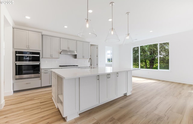 27226 SW Yarrow Ln, Wilsonville, OR 97070 - kitchen with a sink, light countertops, tasteful backsplash, double oven, and a kitchen island with sink