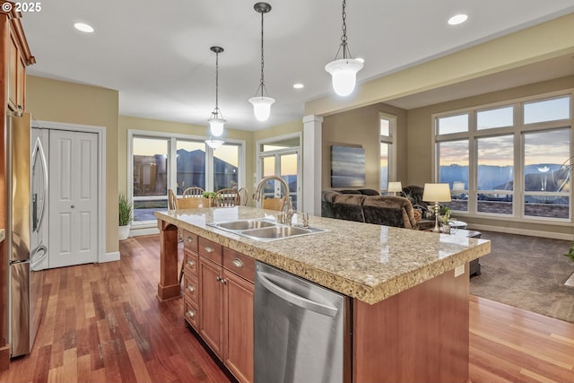 kitchen featuring sink, hardwood / wood-style flooring, hanging light fixtures, stainless steel appliances, and a center island with sink