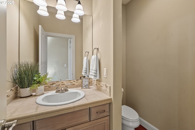 bathroom with vanity, decorative backsplash, and toilet