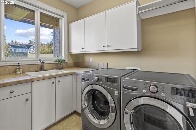 laundry area with cabinets, washing machine and clothes dryer, and sink