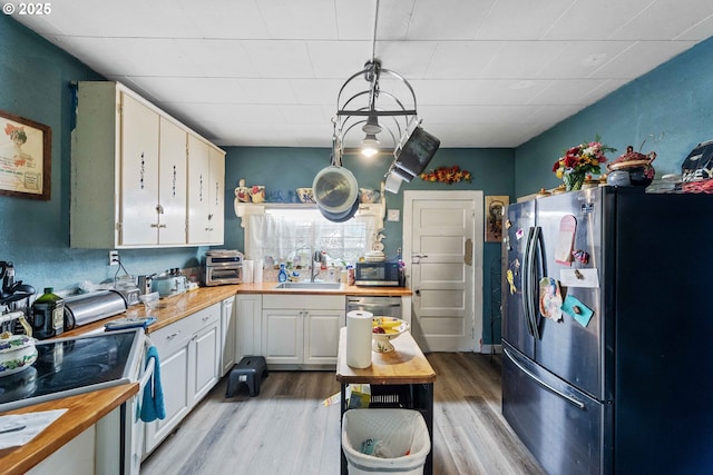 51014 Dement Creek Rd, Myrtle Point, OR 97458 - kitchen with appliances with stainless steel finishes, a sink, butcher block countertops, light wood-style floors, and white cabinets
