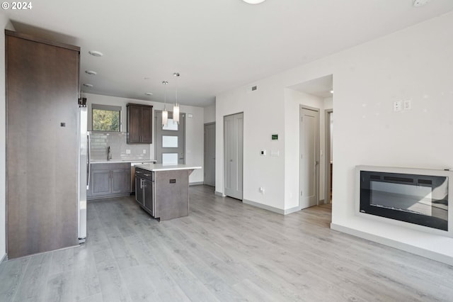 kitchen featuring decorative light fixtures, a kitchen island, decorative backsplash, light hardwood / wood-style flooring, and dark brown cabinets