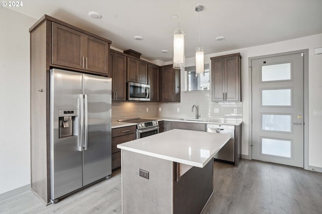 kitchen featuring appliances with stainless steel finishes, tasteful backsplash, pendant lighting, dark brown cabinetry, and a center island