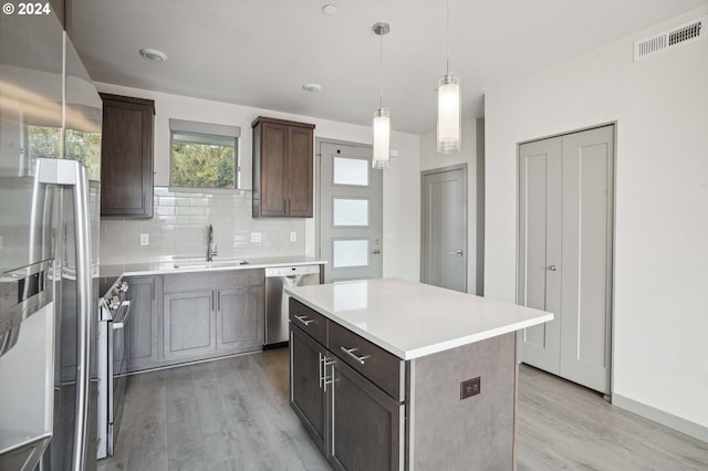 kitchen featuring appliances with stainless steel finishes, decorative backsplash, sink, hanging light fixtures, and a center island