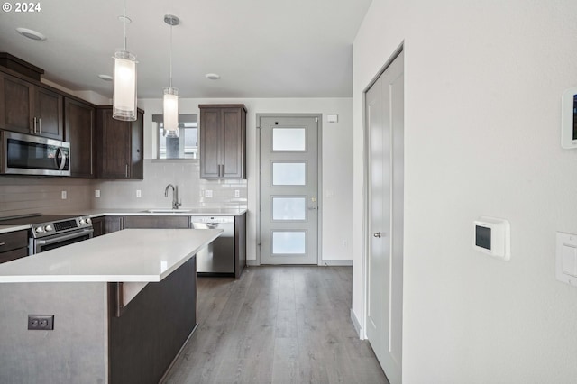 kitchen with tasteful backsplash, appliances with stainless steel finishes, dark brown cabinets, and a center island