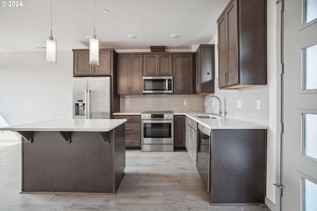 kitchen with a center island, stainless steel appliances, decorative backsplash, sink, and hanging light fixtures