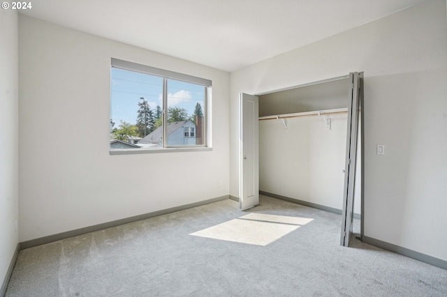 unfurnished bedroom featuring light carpet and a closet