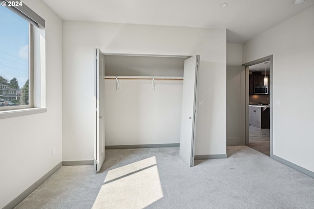 unfurnished bedroom featuring a closet and light colored carpet