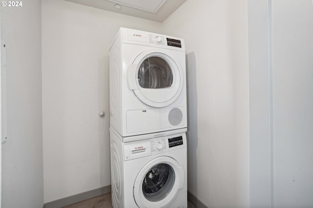 laundry room featuring stacked washer and dryer and wood-type flooring