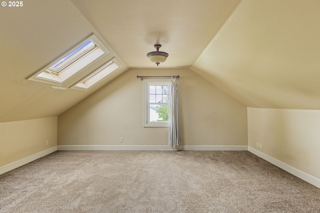 additional living space featuring carpet, a skylight, lofted ceiling, and baseboards